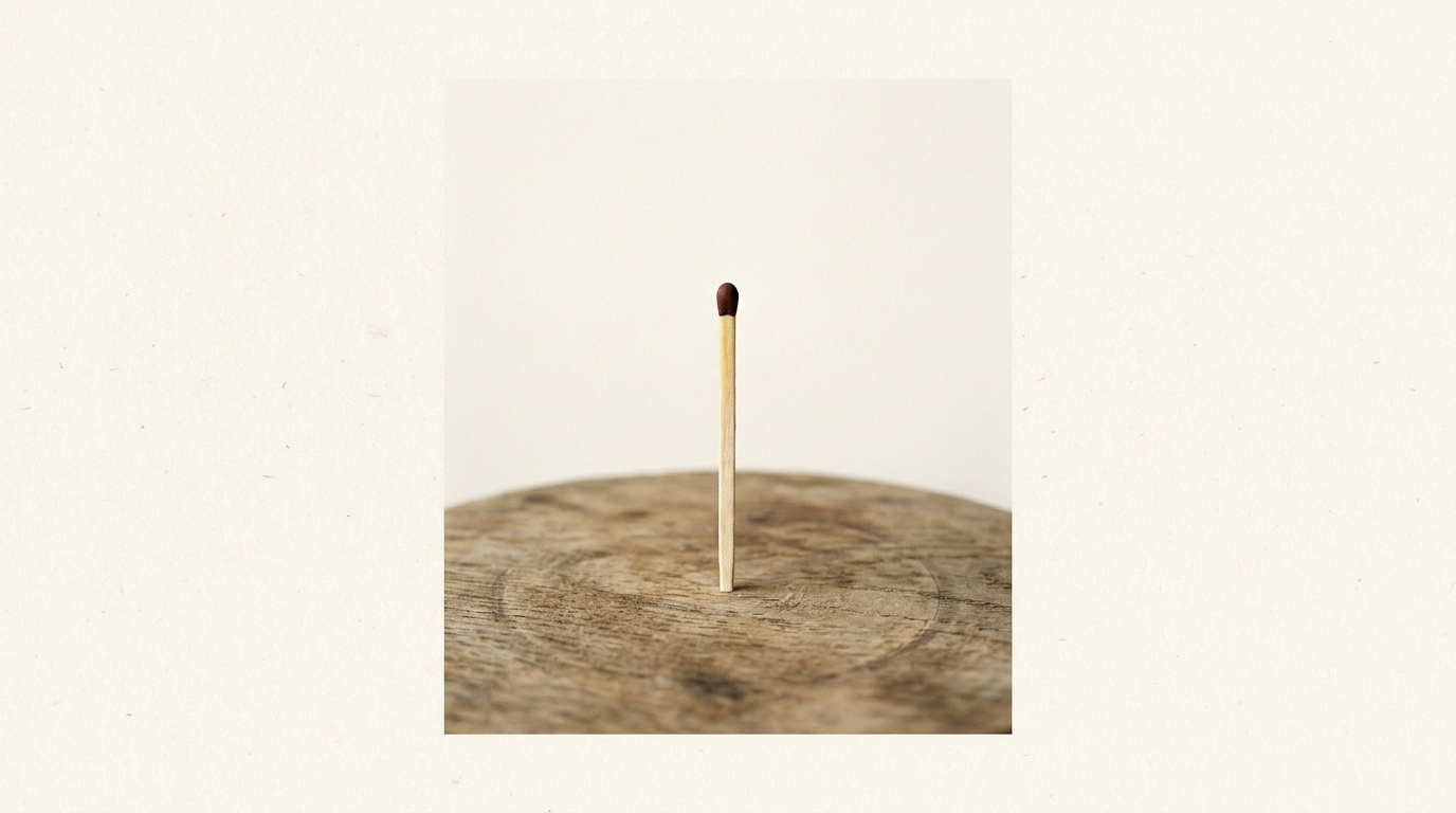 Single unlit match standing upright on a wooden surface